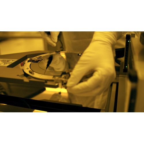 Eine Person in einem weißen Laborkittel hält ein Stück Glas in der Hand.