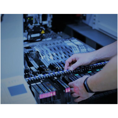 Eine Person arbeitet an einer Maschine, während im Hintergrund eine weitere Maschine zu sehen ist.