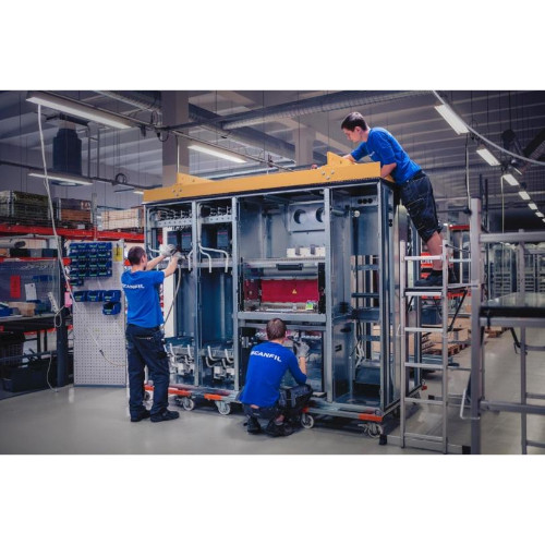 Drei Männer arbeiten an einer Maschine in einer Fabrik.