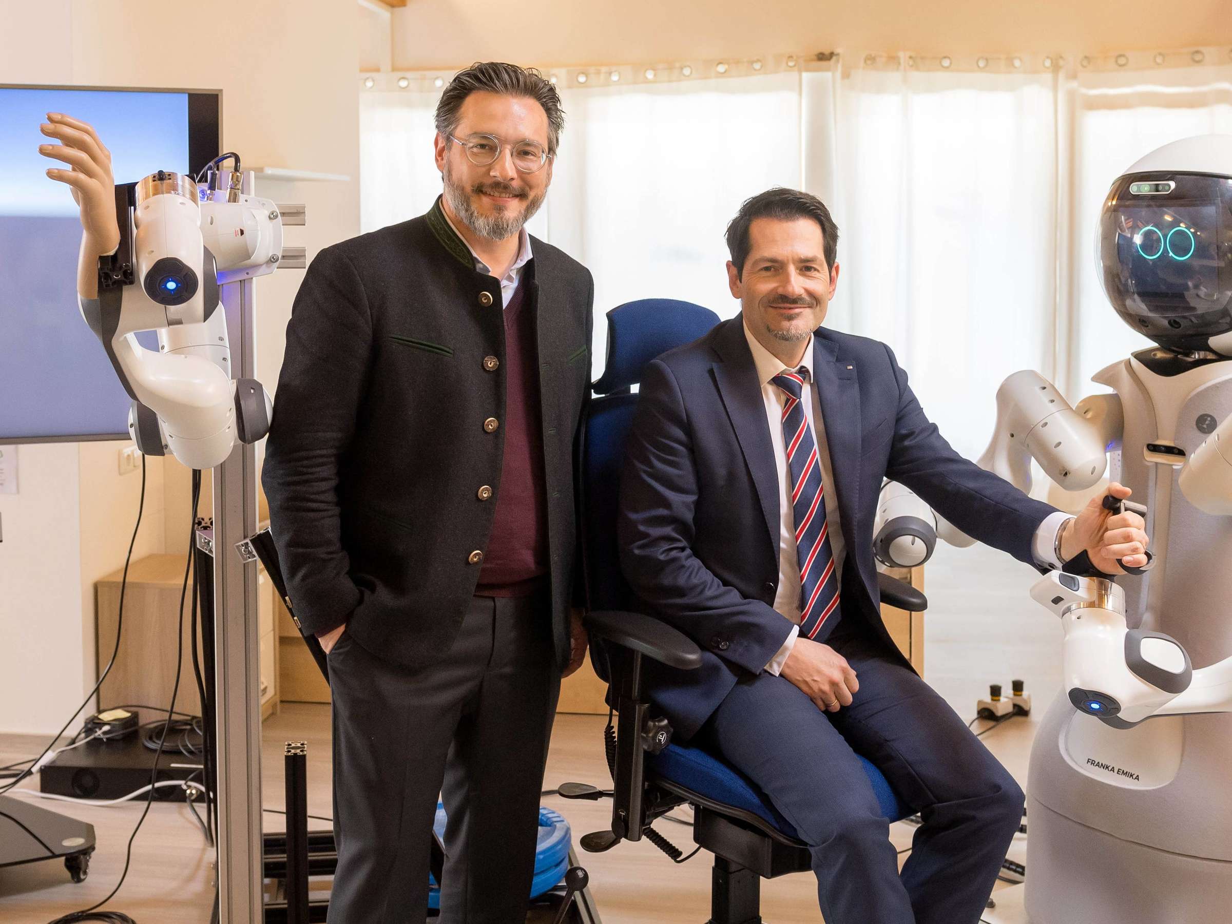 Ein Foto von zwei Männern, die zusammen mit Assistenzrobotern interagieren 