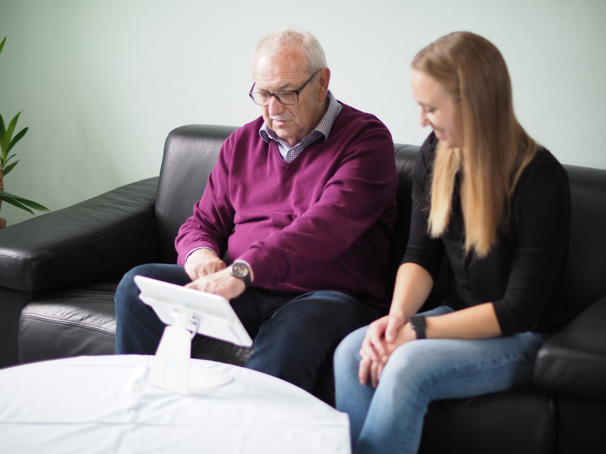 Eine junge Frau erklärt einem älteren Mann die Nutzung eines medizinischen Technologiegeräts