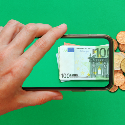 eine Hand hält ein Smartphone und fixiert Geldscheine