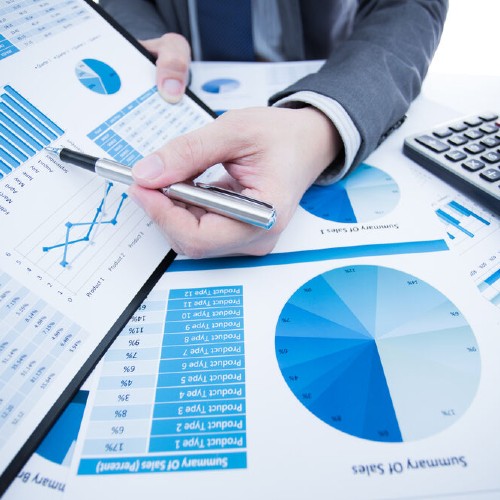 Eine Hand deutet auf eine Grafik mit einem Stift im Hintergrund ist ein Taschenrechne