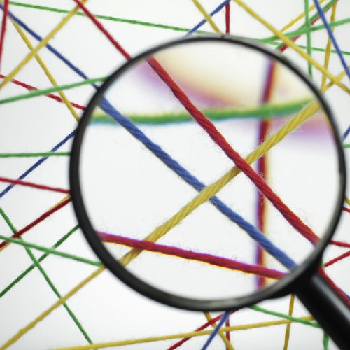 Eine Lupe, die auf mehrere farbige Fäden schaut
