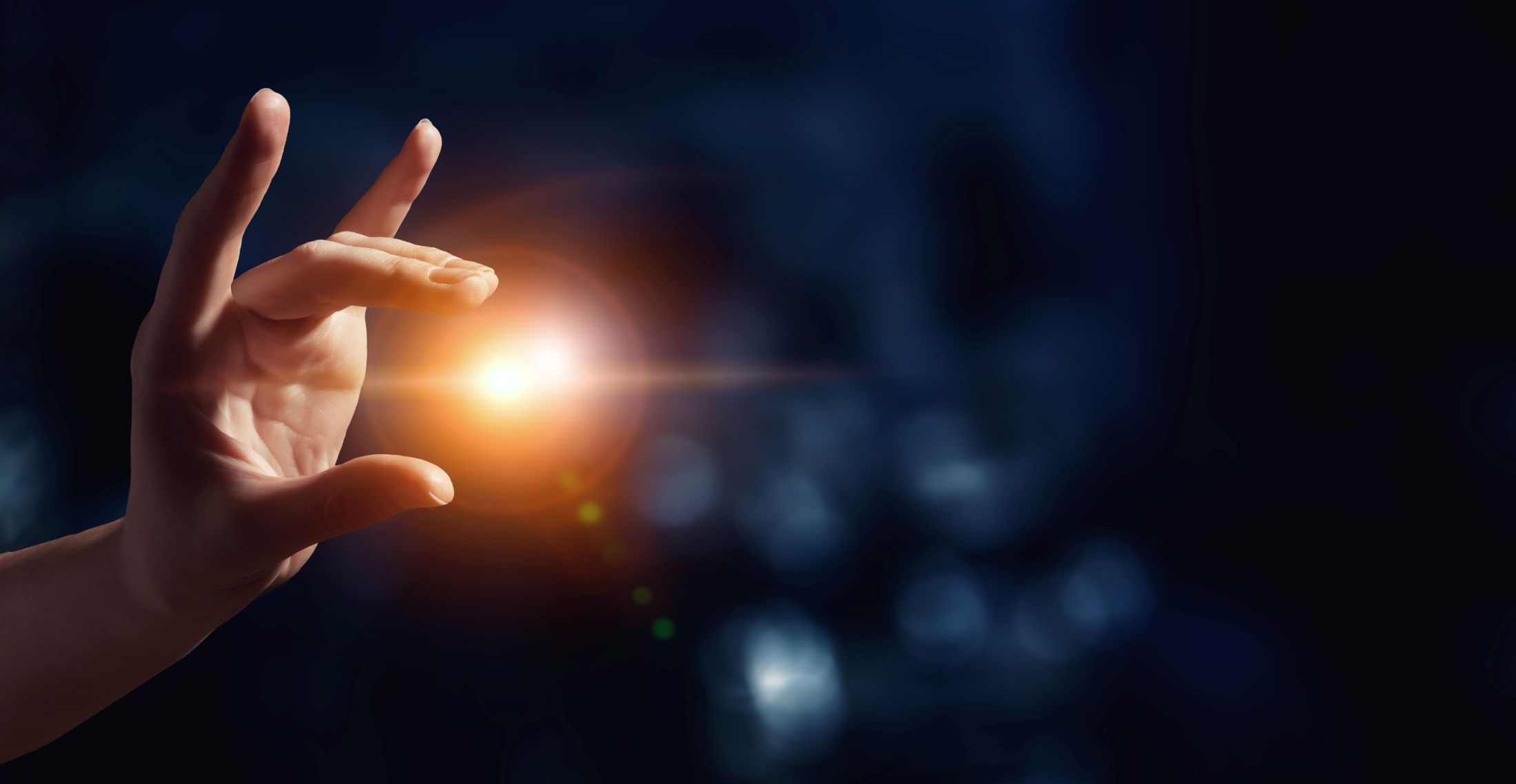 Auf dem Bild ist eine Hand zu sehen, die Finger sind ausgestreckt und versuchen eine Lichtkugel einzufangen