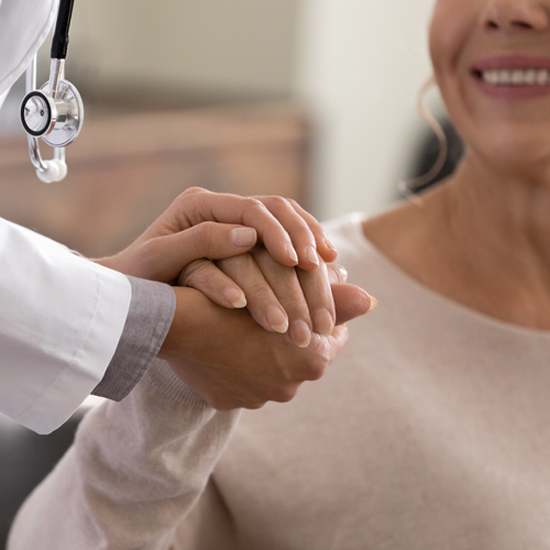 Ein Arzt hält die Hand einer älteren Patientin