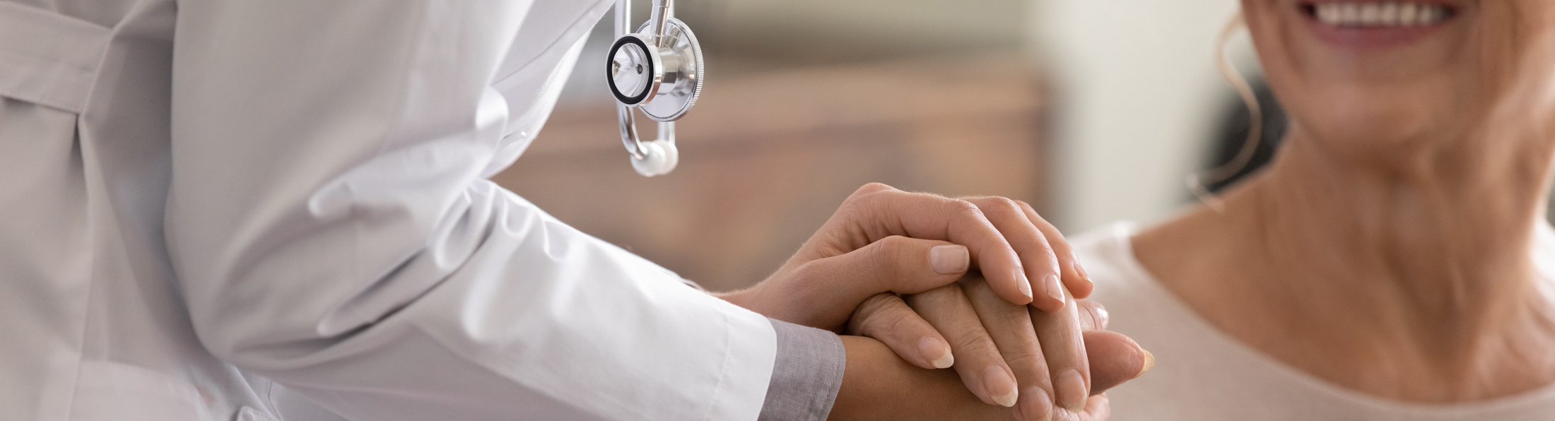 Ein Arzt hält die Hand einer älteren Patientin