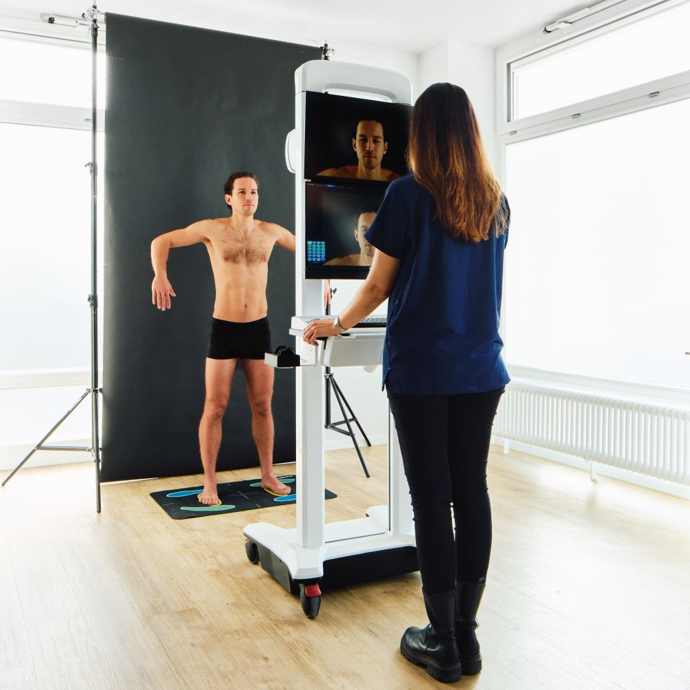 Fachkraft arbeitet an einem medizinischen Gerät, während eine stehende Person davor positioniert ist.