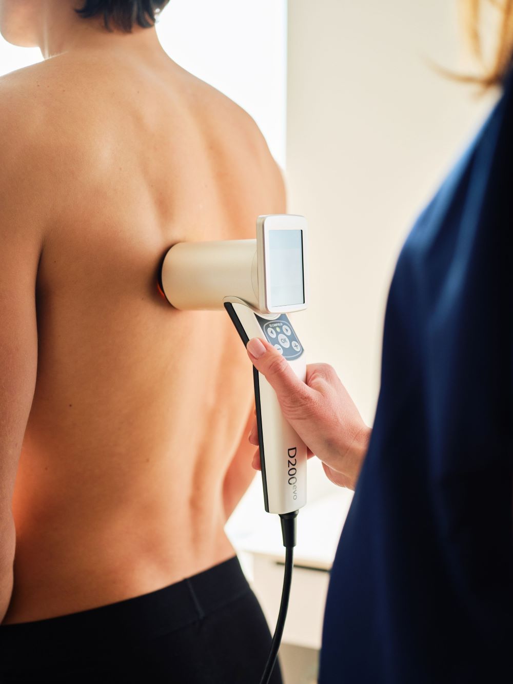 Nahaufnahme einer Untersuchung am Oberkörper einer Person, Fachkraft hält ein medizinisches Gerät.