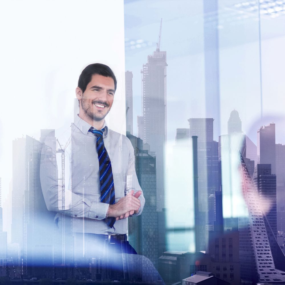 Businessmann steht vor einer Glasscheibe in der sich die Skyline spieglet