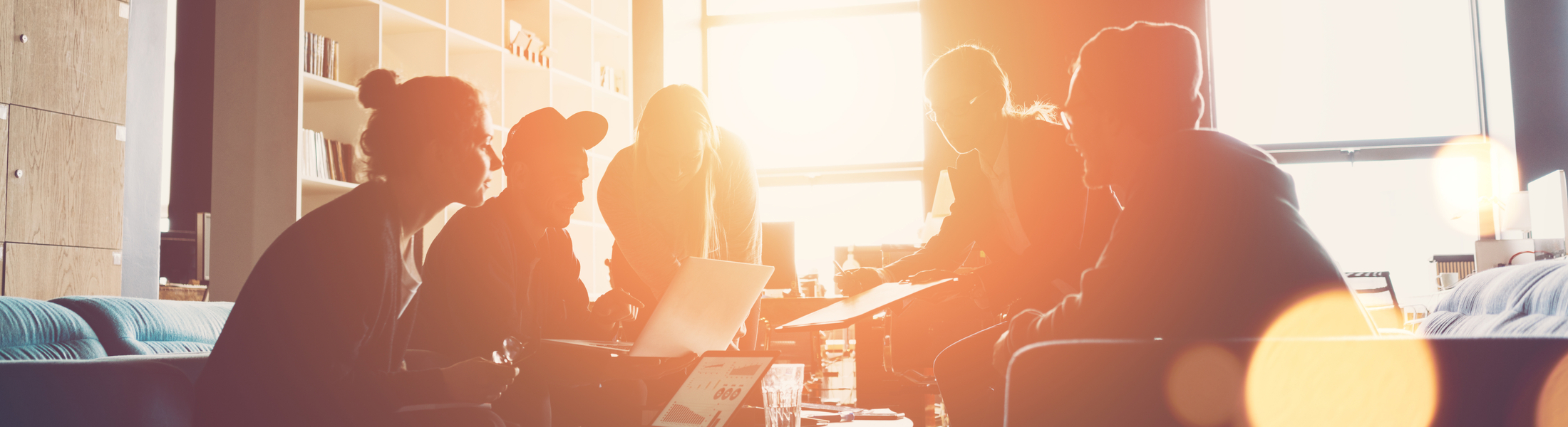 Eine Gruppe von Personen sitzt um einen Tisch mit Laptops und diskutiert angeregt.