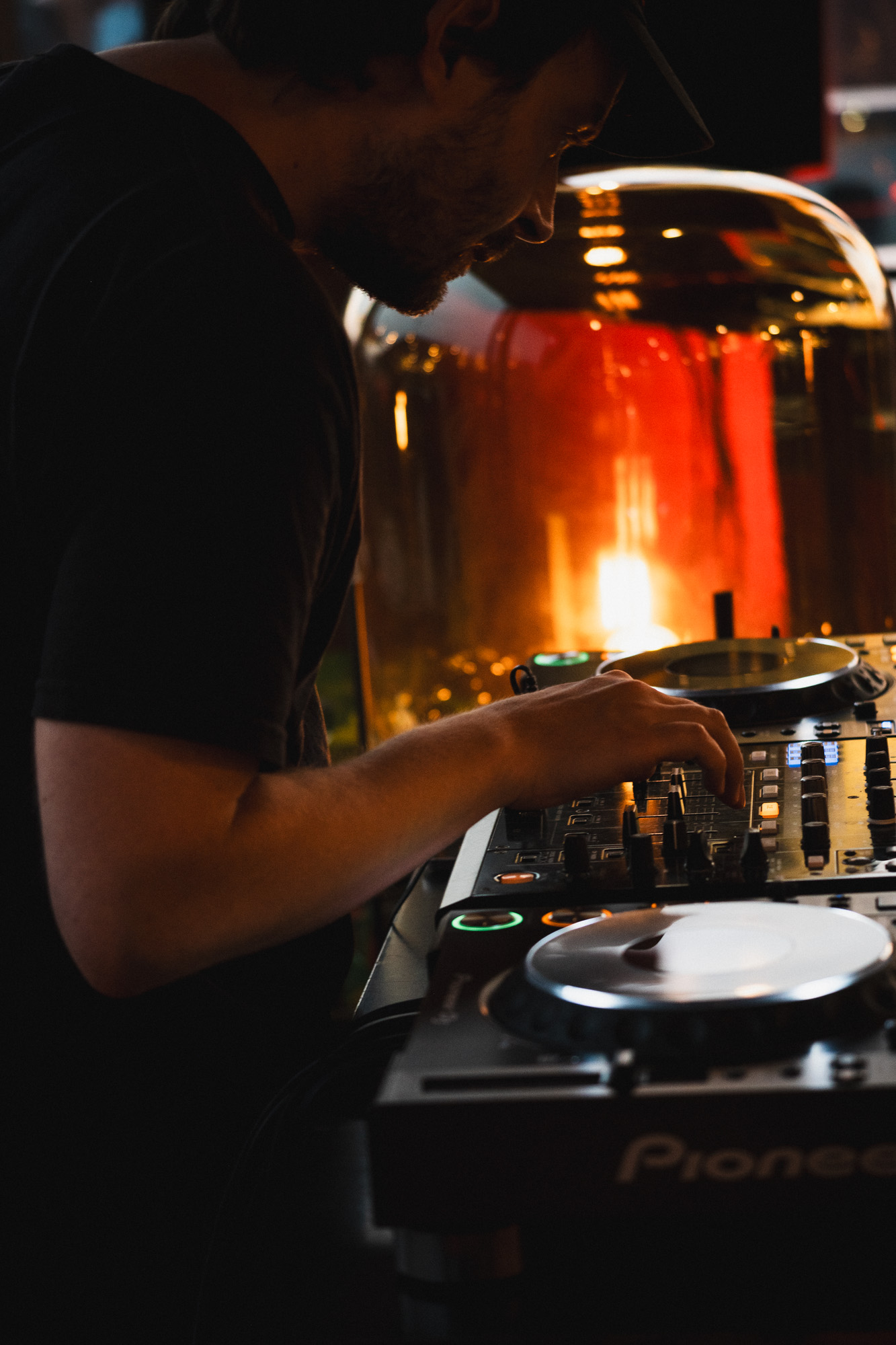 Ein DJ steht hinter einem Mischpult und bedient die Musiktechnik.