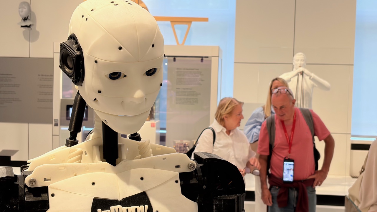 Führung: Robotik und Design im Deutschen Museum: Im Vordergrund ist der Kopf eines Ro-boters zu sehen, während dahinter ein paar Menschen stehen.