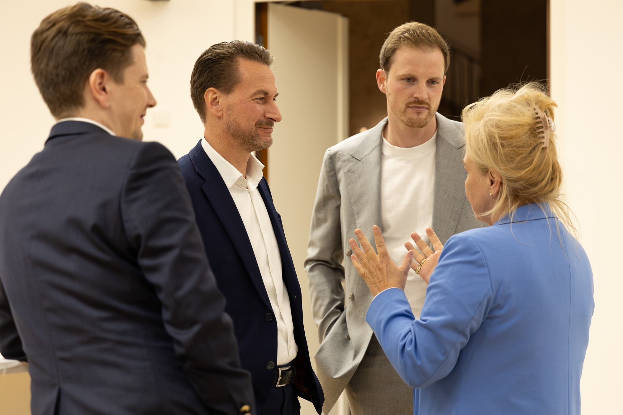 Petra Lorenz, Geschäftsführerin des CommClubs Bayern e.V., steht mit drei Männern in einem Raum und unterhält sich mit ihnen.
