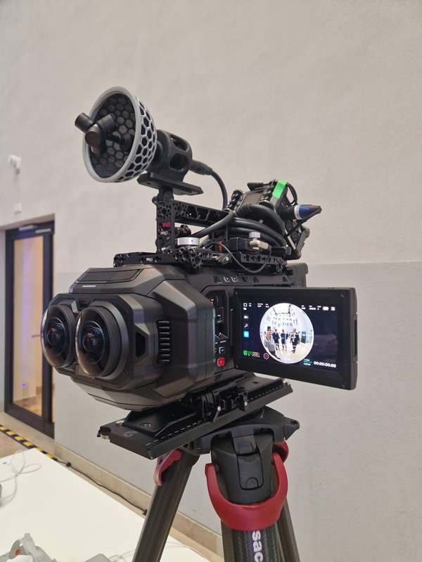 Auf einem Stativ steht eine professionelle Kamera, einem externen Mikrofon und einem angebrachten Monitor, auf dem eine Aufnahme zu sehen ist.