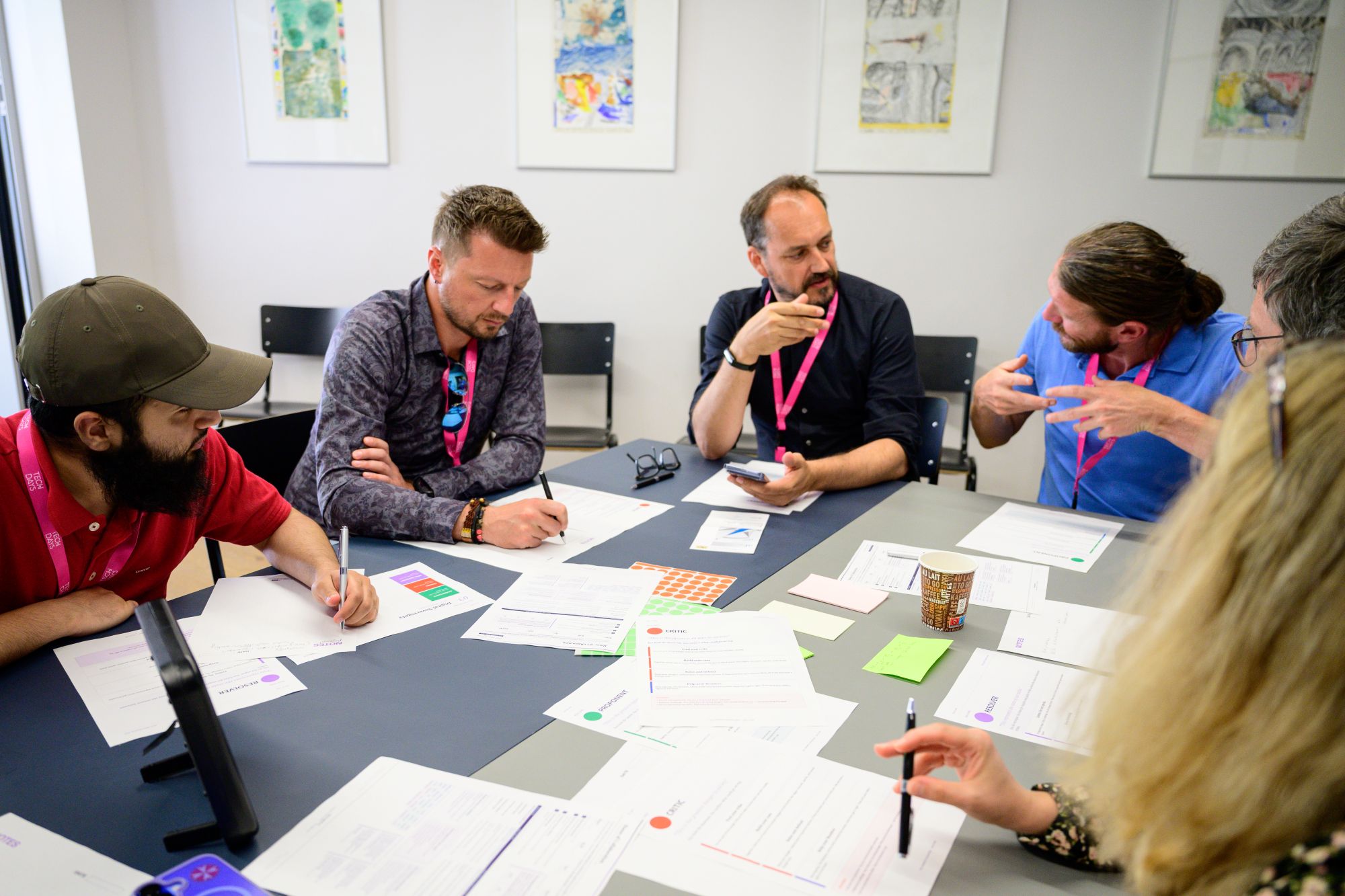 Mehrere Teilnehmende sitzen gemeinsam an einem Tisch und tauschen sich im Rahmen eines Workshops aus. Auf dem Tisch liegen Arbeitsunterlagen, Notizen und Schreibmaterialien.