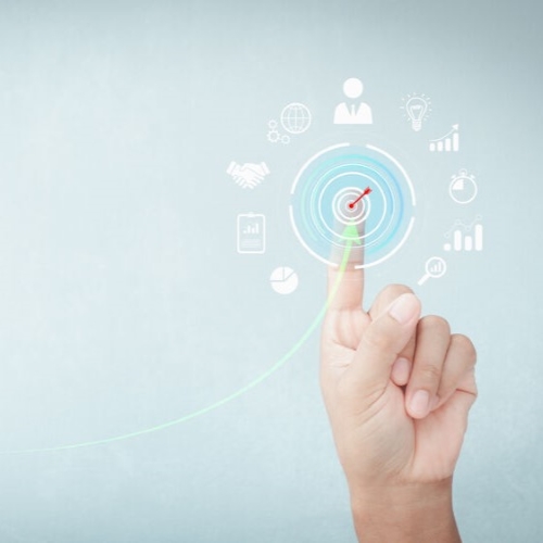 Hand zeigt auf ein digitales Zielsymbol mit Icons für Geschäft und Innovation.
