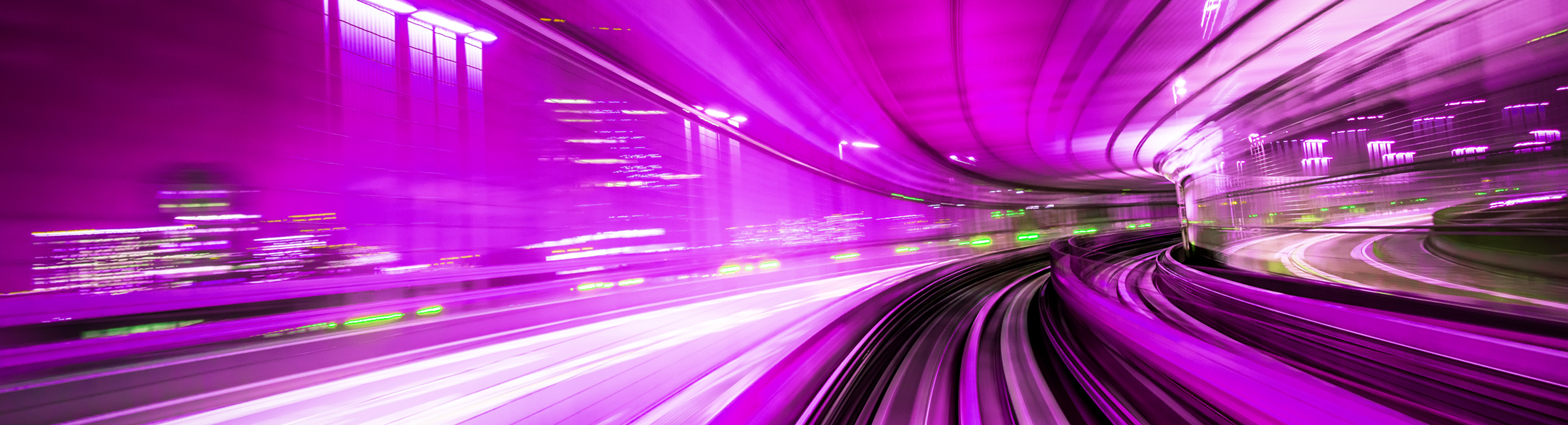 Verschwommene Nachtaufnahme einer Straße, die durch eine Stadt führt, umgeben von urbanen Lichtern.