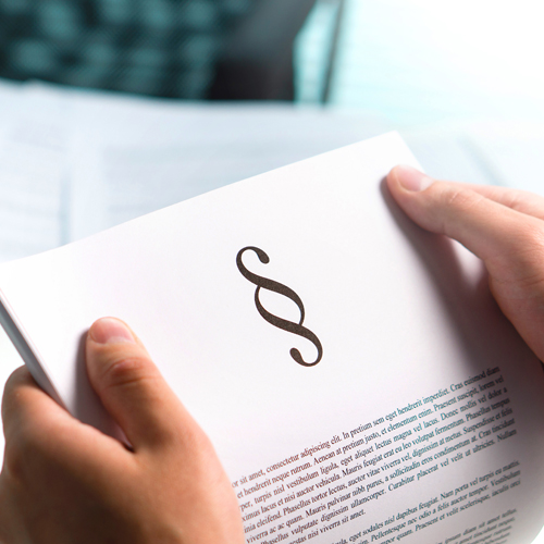 eine Frau hält ein Blatt Papier, auf dem ein Paragraphenzeichen zu sehen ist.