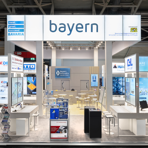 Frontansicht Gemeinschaftsstand Bayern Innovativ auf der electronica 2024 mit den Standmodulen mehrerer mitausstellenden Unternehmen und deren Exponate