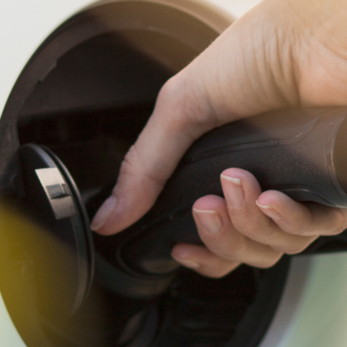 Eine Hand, die ein Ladekabel in den Anschluss eines Elektroautos anschließt