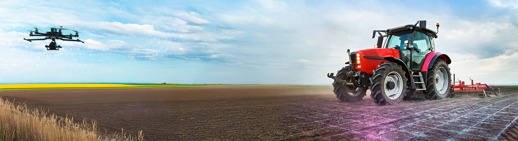 Ein Traktor steht auf einem Feld, das mit einem Datengitter versehen ist. Daneben fliegt eine Drohne.