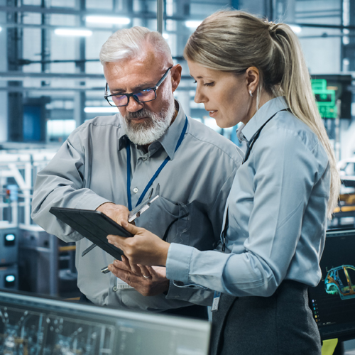 Zwei Personen in Businesskleidung betrachten gemeinsam ein Tablet.