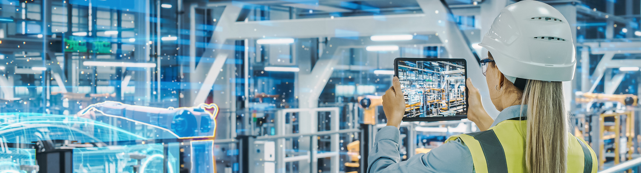 Eine Frau hält ein Tablet in den Innenraum eines Industriebetriebs