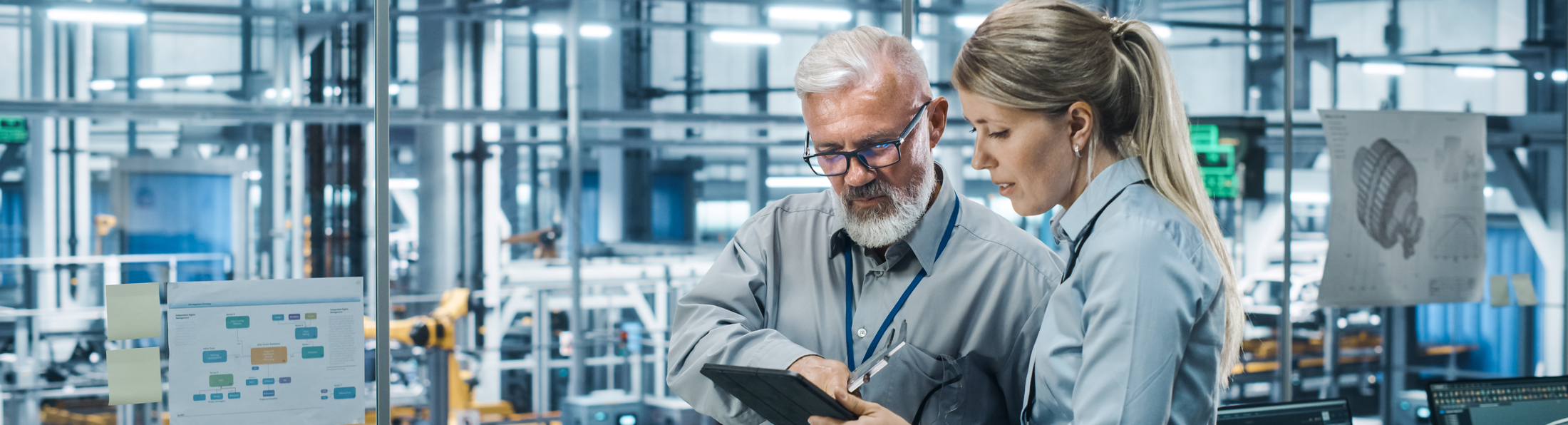 Zwei Personen in Businesskleidung betrachten gemeinsam ein Tablet.