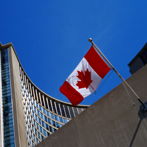 Kanadische Flagge an einem Gebäude unter blauem Himmel