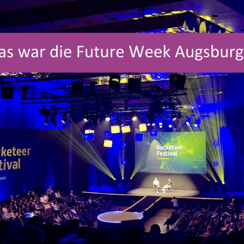 Bühne des Rocketeer Festivals bei der Future Week Augsburg mit Publikum und Podiumsdiskussion unter Lichteffekten.