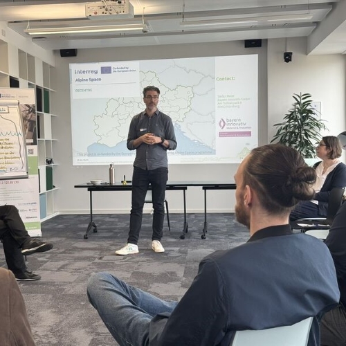 Ein Mann hält in einem modern eingerichteten Workshop-Raum eine Präsentation vor Teilnehmern