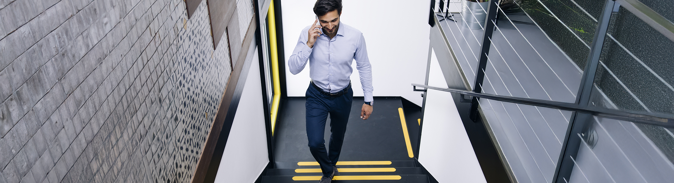 Ein Mann telefoniert am Smartphone und läuft eine Treppe hoch.