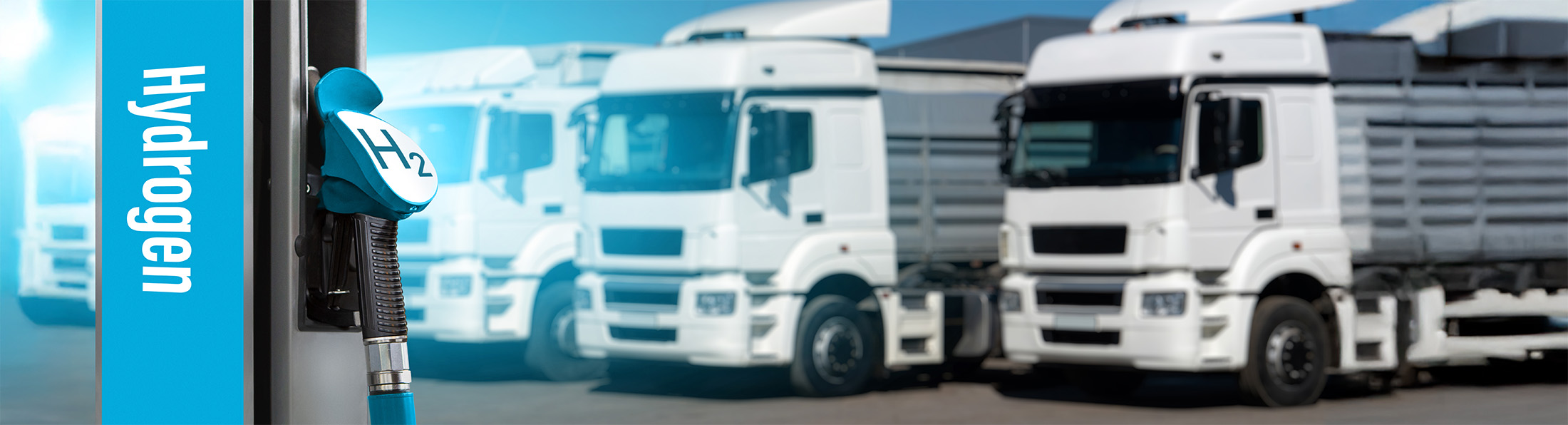 Eine Ladesäule mit der Aufschrift Hydrogen vor einer LKW Flotte