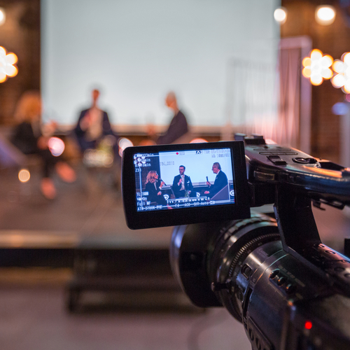 Eine Videokamera nimmt eine Diskussionsrunde auf.