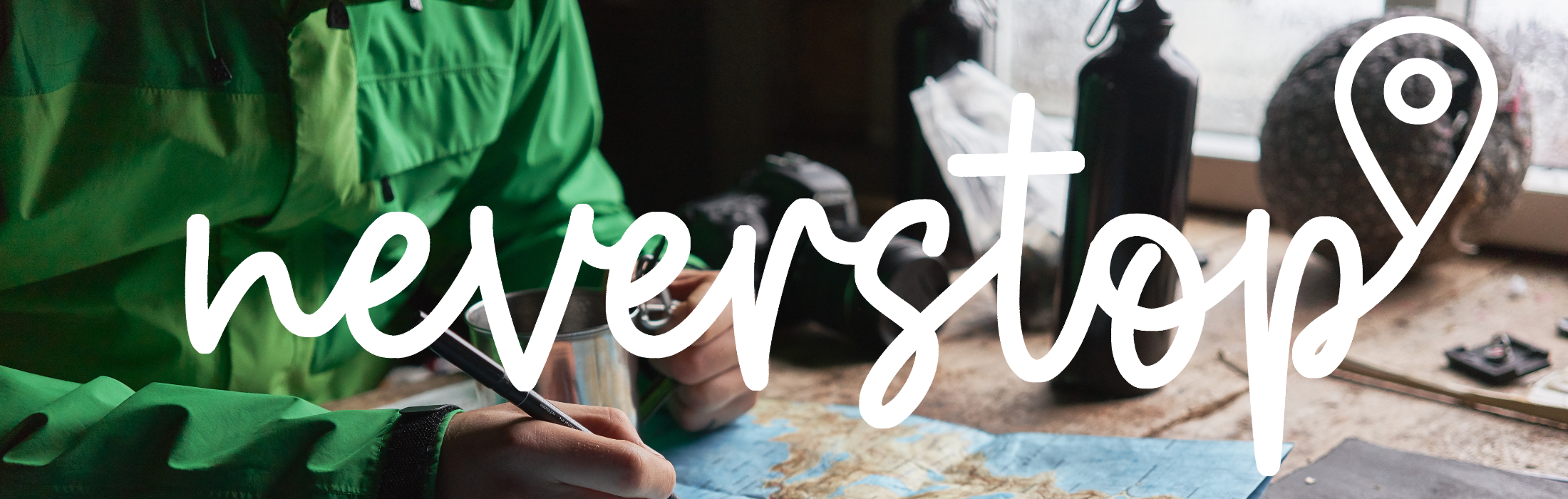 Mensch markiert etwas auf einer Landkarte, darüber ist ein Schriftzug mit dem Wort "neverstop"