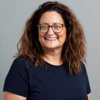 Braunhaarige Frau mit Brille und langen, lockigen Haaren