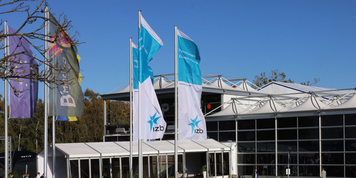 Zu sehen ist das Messegelände der Internationalen Zuliefererbörse in Wolfsburg mit wehenden Fahnen vor dem Eingang