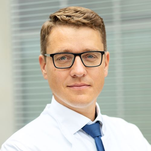 Auf dem Bild ist ein Herr in weißem Hemd und blauer Krawatte zu sehen