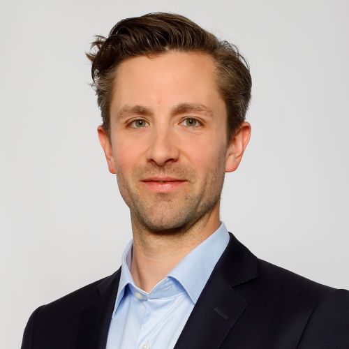 Auf dem Bild ist ein Herr in schwarzem Sakko und hellblauem Hemd zu sehen 