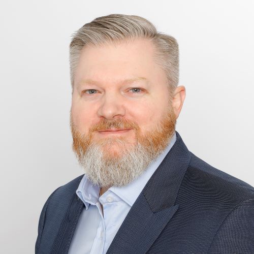 Auf dem Bild ist ein Herr in dunklem Sakko und hellblauem Hemd zu sehen