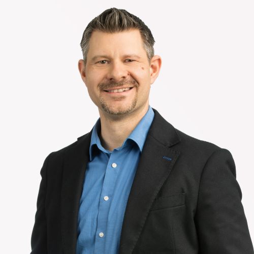 Auf dem Bild ist ein Mann mit schwarzem Sakko und blauem Hemd zu sehen