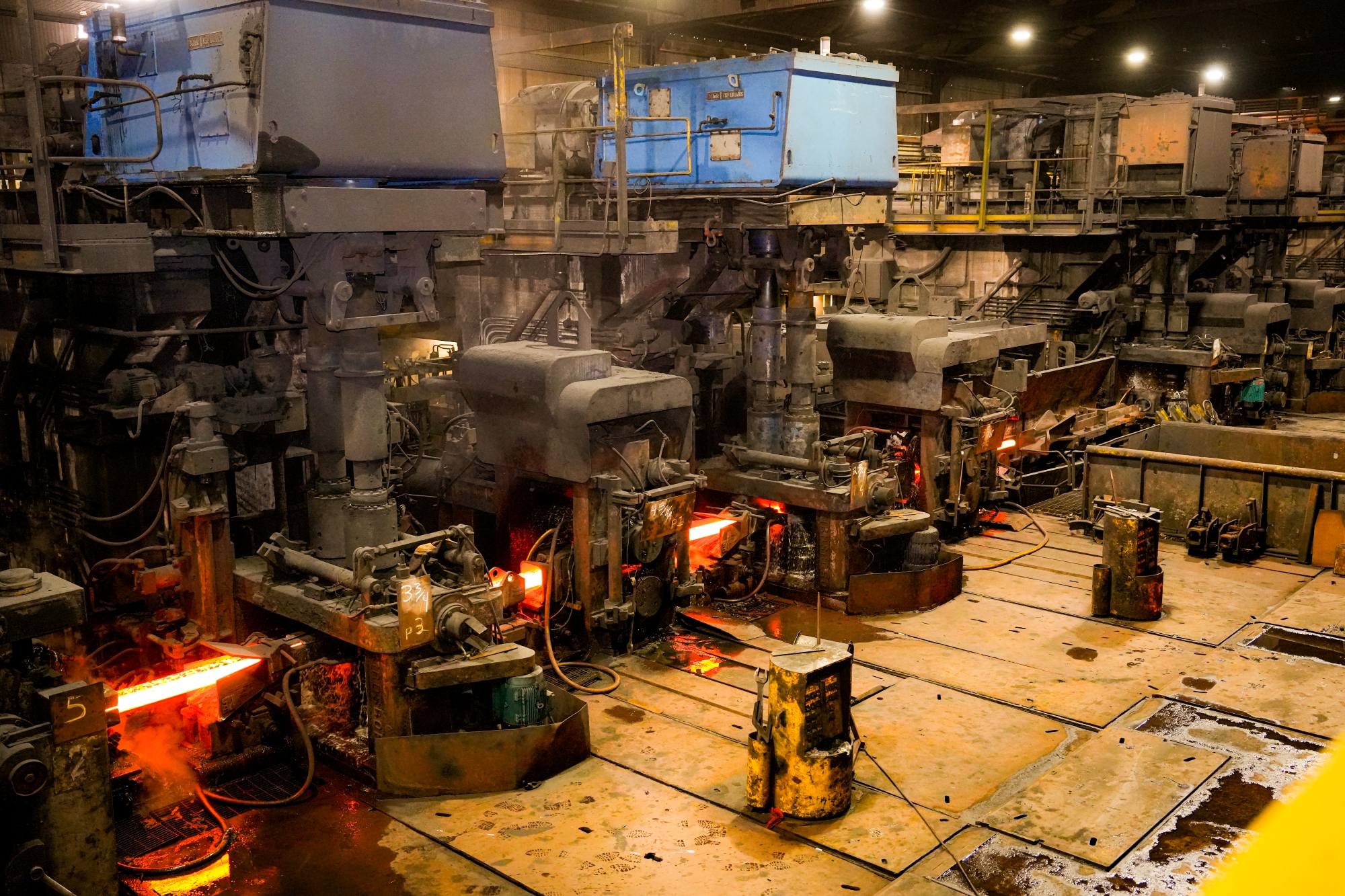 Gruppe von Personen mit Schutzhelmen steht in einer Industriehalle mit glühenden Maschinen und Produktionsanlagen im Hintergrund. Das Foto entstand während der Delegationsreise in Kanada.