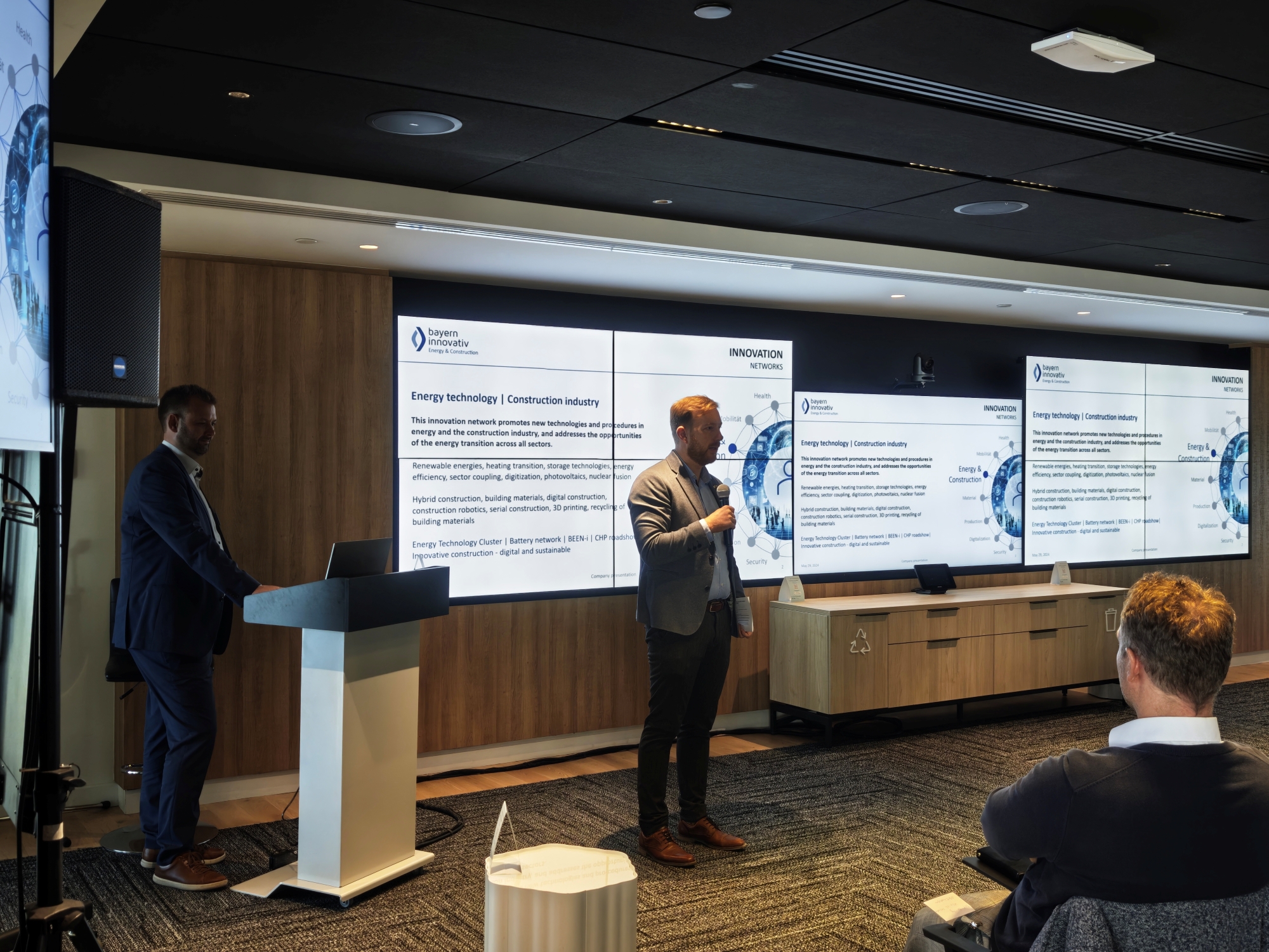 Präsentationsszene: Eine Person spricht vor einer Leinwand mit mehreren Folien, Teilnehmende hören zu. Das Foto zeigt einen Moment der Delegationsreise in Kanada.