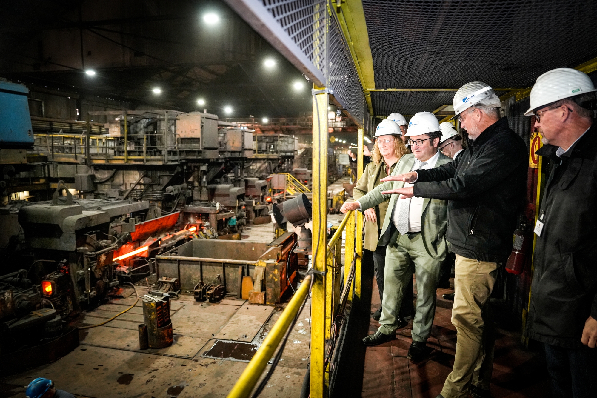 Teilnehmende der Delegation tragen Schutzkleidung und Helme während einer Besichtigung einer Produktionsstätte mit laufenden Maschinen. Aufgenommen bei der Delegationsreise in Kanada.