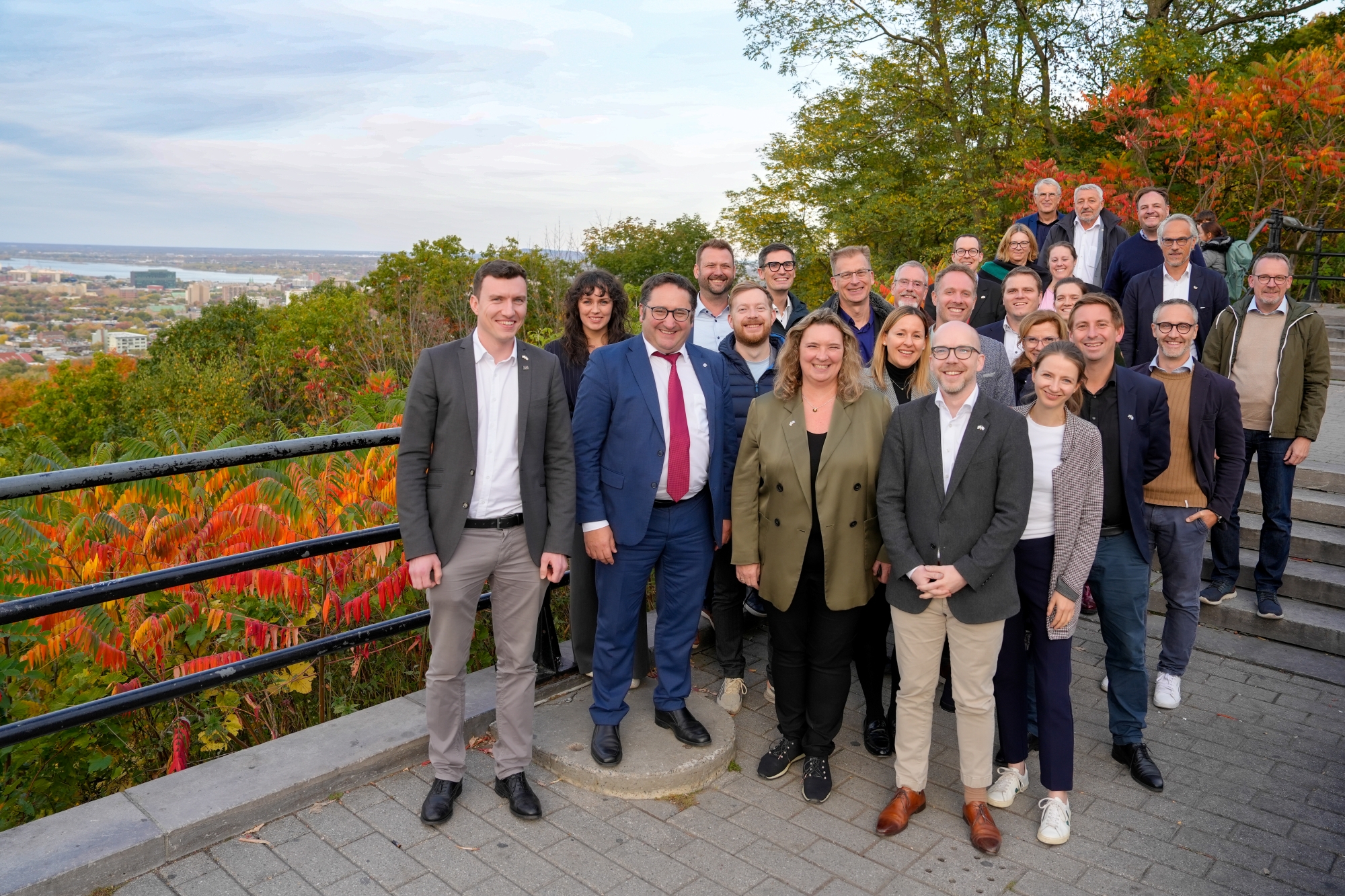Gruppenfoto im Freien mit Herbstbäumen im Hintergrund, mehrere Teilnehmende in formeller Kleidung. Aufgenommen bei der Delegationsreise in Kanada.