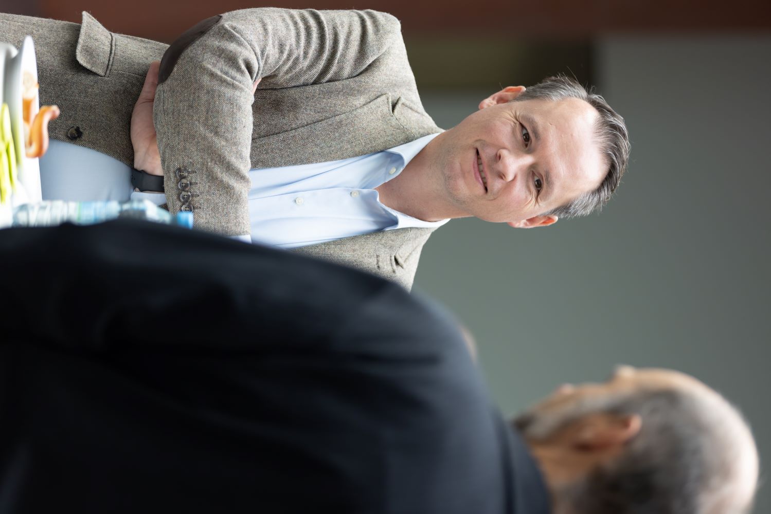 Mann in einem Jackett, der in die Kamera schaut, mit einem neutralen Hintergrund.