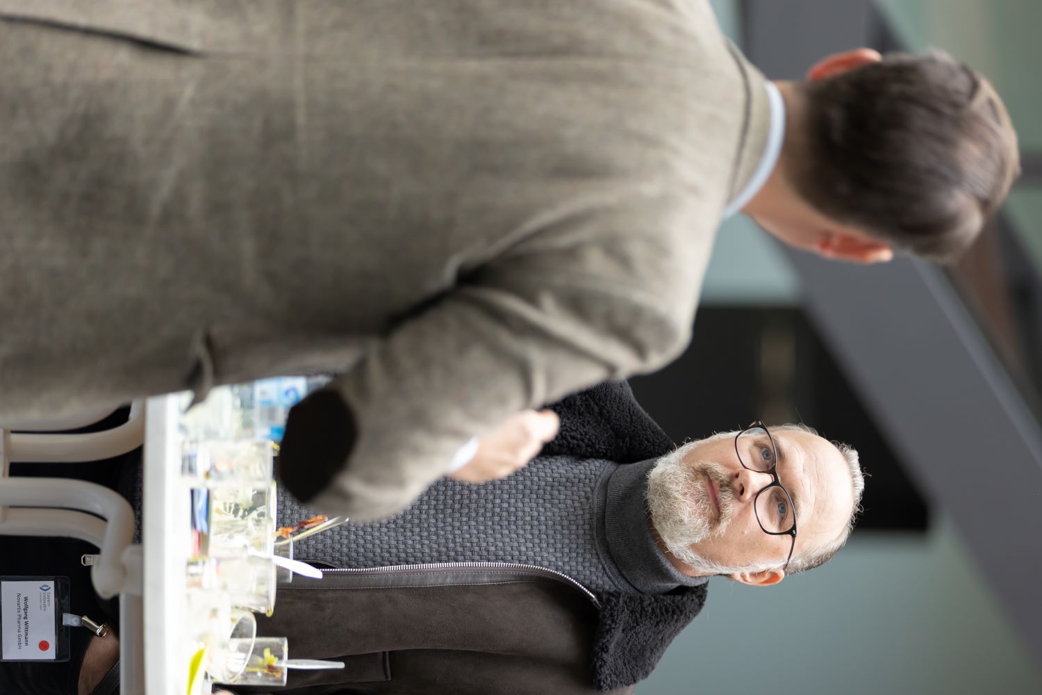 Ein Mann trägt eine braune Jacke und blickt nachdenklich zur Seite.