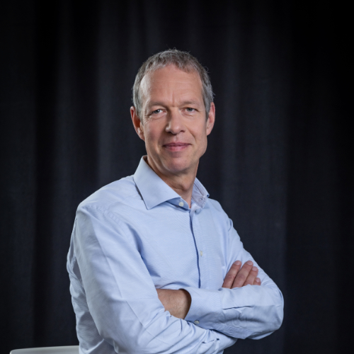 Das Bild zeigt einen Mann in einem Blauen Hemd.