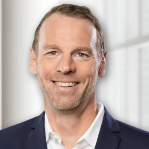 Das Bild zeigt einen lächelnden Mann mit kurzen, hellbraunen Haaren